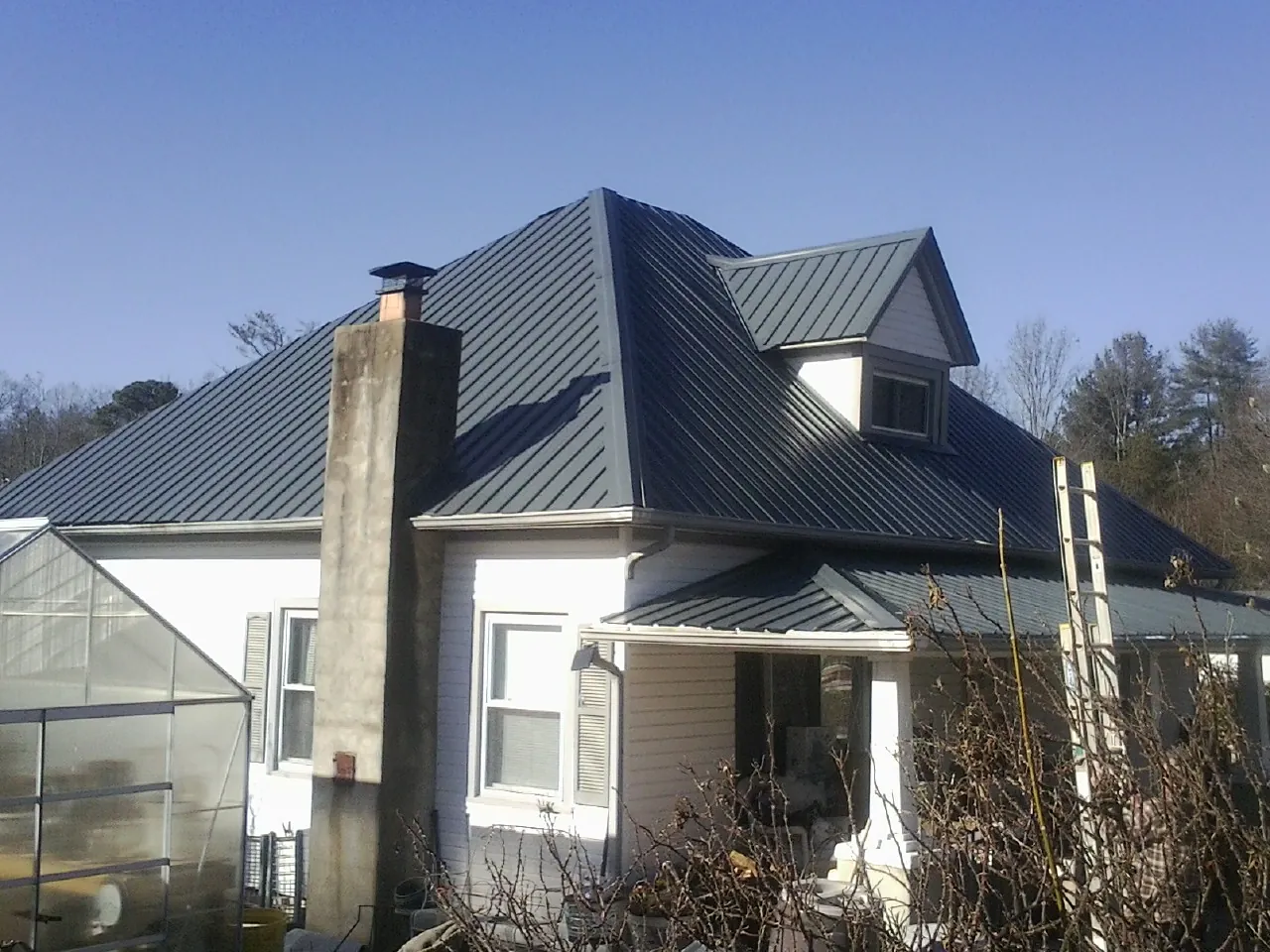Dark blue standing seam metal roof on a white farmhouse with dormer — Slate & Tile Roof Repair by Roofing Brothers in Mechanicsburg